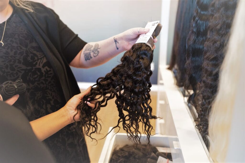 A Hair Piece / Samantha Hestand, left, of Yummy Extensions in Dallas, holds a hair piece as a customer shops. Photo by (Ben Torres / Special Contributor)